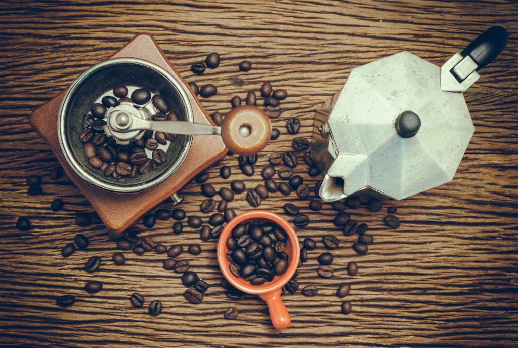 Old moka coffee pot with manual coffee grinder and coffee bean in vintage style Diferentes maneiras de começar o seu dia com café