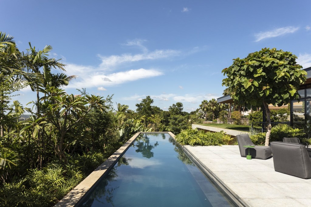 the-linear-swimming-pool-hovers-above-the-hillside-disappearing-into-the-tropical-foliage Integração com natureza é o foco em casa de Perkins+Will em Ribeirão Preto